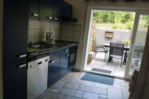 Ett kompakt kök med diskmaskin, spis och en matplats med bord och stolar.