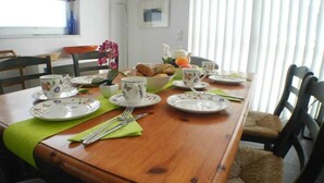 Une table à manger dressée avec des assiettes, des tasses et des couverts, entourée de chaises.