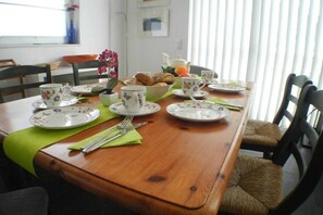 Een eettafel gedekt met borden, bekers en bestek, omringd door stoelen.