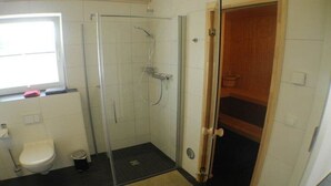 Une salle de bain avec des toilettes, un espace douche et une porte en bois.