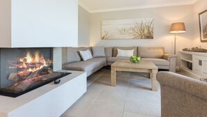 Una sala moderna con chimenea, un sofá, una mesa de centro y una lámpara.