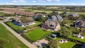 Un pueblo rural con casas tradicionales, un campo de golf y un faro a lo lejos.