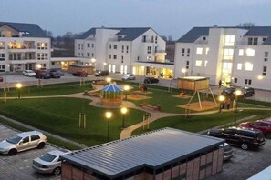 Ein Wohnkomplex mit mehreren weißen Gebäuden, einem zentralen Innenhof mit einem Pavillon und einem Parkplatz.