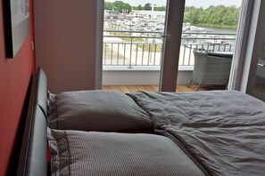 A bedroom with a view of a marina through a balcony. - Holiday apartment with 1 bedroom (Werder)