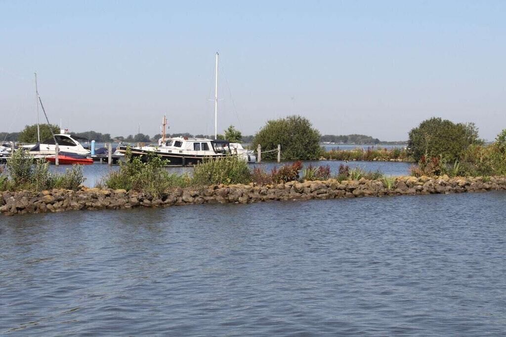En lysthavn med fortøjede både, omgivet af vand og beplantning.