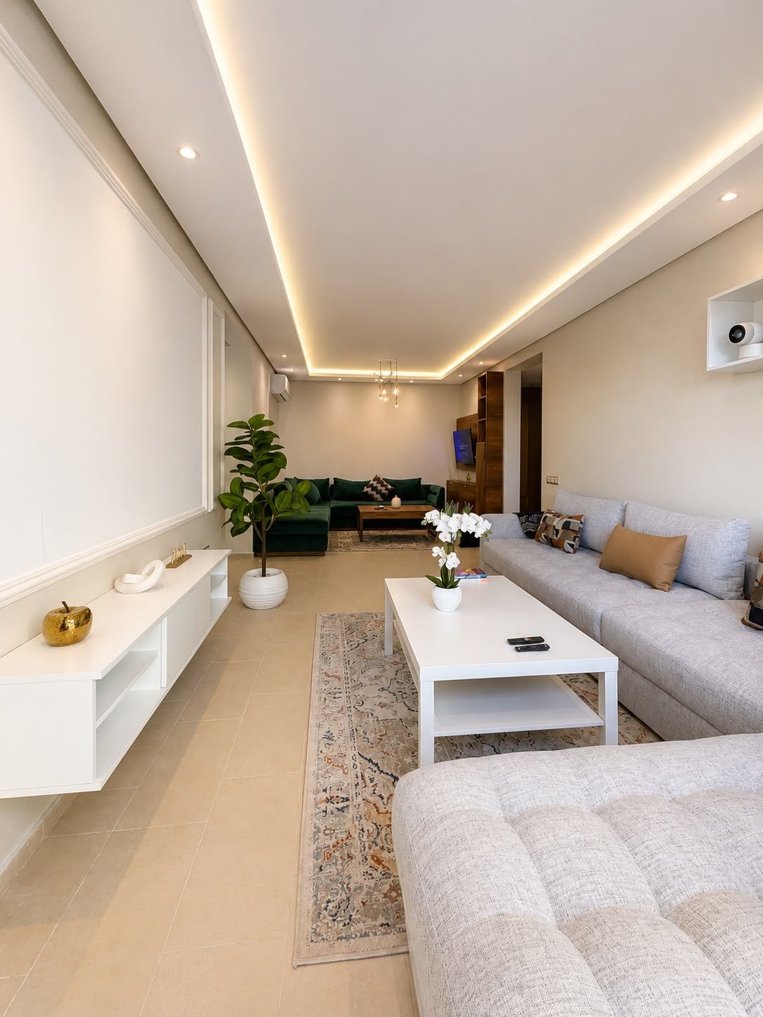 Un salon moderne avec un canapé blanc, une table basse et, au fond, un canapé vert.