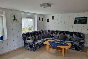 Un salon avec un canapé à motifs, une table basse en bois et une fenêtre avec des rideaux.