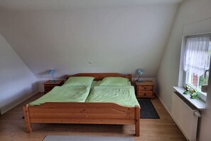 Ein Schlafzimmer mit einem Holzbett, zwei Nachttischen, einem Fenster mit Blick und einer Heizung.