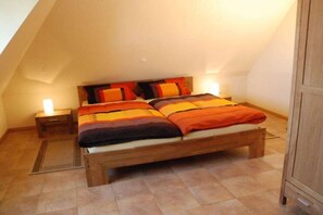Ein Einzelbett mit Holzbettrahmen und Kopfteil, begleitet von zwei Nachttischen, einer davon mit Lampe.