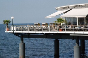 A waterfront restaurant with outdoor seating and a view of the sea. - Holiday home with 1 bedroom (Seebad Heringsdorf)