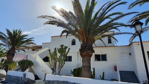 Un bâtiment blanc avec un toit recouvert de tuiles rouges, un escalier et des palmiers.