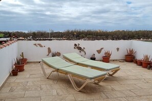 A rooftop terrace with two lounge chairs, potted plants, and a view of the landscape. - Holiday apartment with 1 bedroom (Costa Calma)
