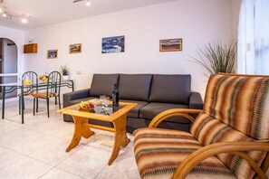Een moderne woonkamer met een bank, een houten salontafel en een gestreepte fauteuil.