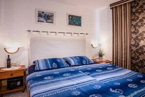 Un dormitori amb llit, nits, una làmpada i una cortina.