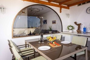 A dining area with a glass table, chairs, a fruit basket, and a view through a large mirror. - Holiday apartment with 1 bedroom (Costa Calma)
