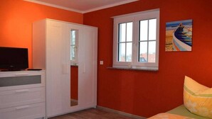 A bedroom with a bed, a wardrobe, a television, and a window. - Holiday home with 4 bedrooms (Ostseebad Rerik)