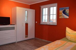 Un dormitorio con cama, armario, televisor y ventana.