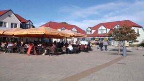 An outdoor seating area with tables and chairs, surrounded by buildings with red roofs. - Holiday home with 4 bedrooms (Ostseebad Rerik)