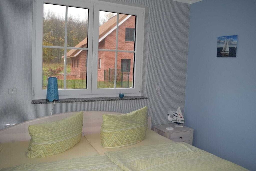Ein Schlafzimmer mit Bett, Fenster, Nachttisch und einem Modell eines Segelboots.