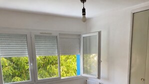 Et soveværelse med seng, radiator, skab og et vindue med persienner.