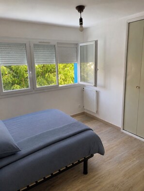 A bedroom with a bed, a radiator, a wardrobe, and a window with blinds. - 3-bedroom family home with parking, perfect for exploring Arras and the surrounding area (Anzin-Saint-Aubin)