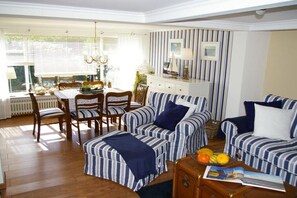 A dining area with a table and chairs, a striped sofa, and a cabinet with decorative items. - Holiday home with 4 bedrooms (Risum-Lindholm)