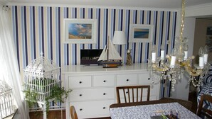 Uma sala de jantar com papel de parede listrado, um lustre e uma mesa posta para dois.