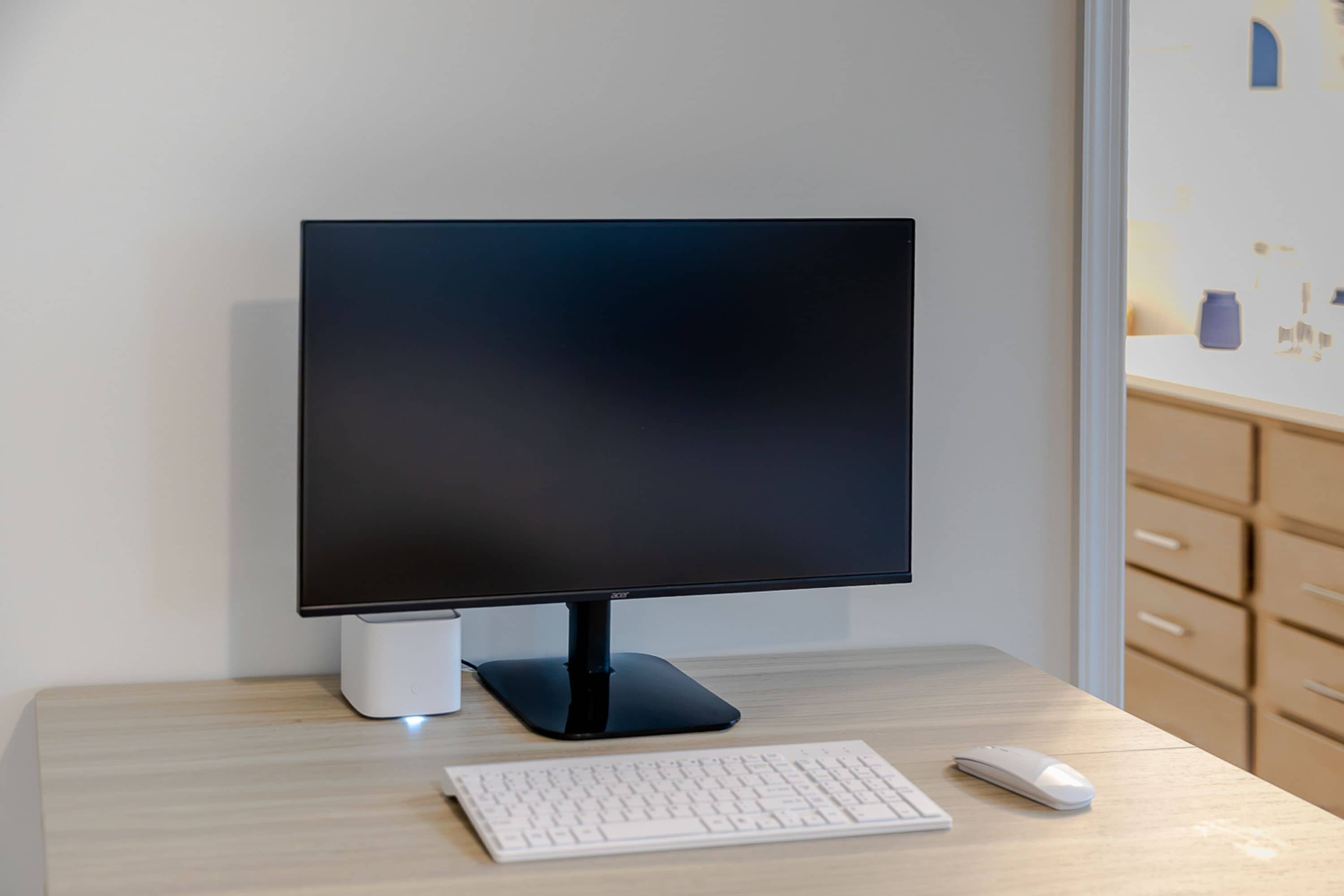 A modern desktop computer setup with a monitor, keyboard, and mouse on a wooden desk.