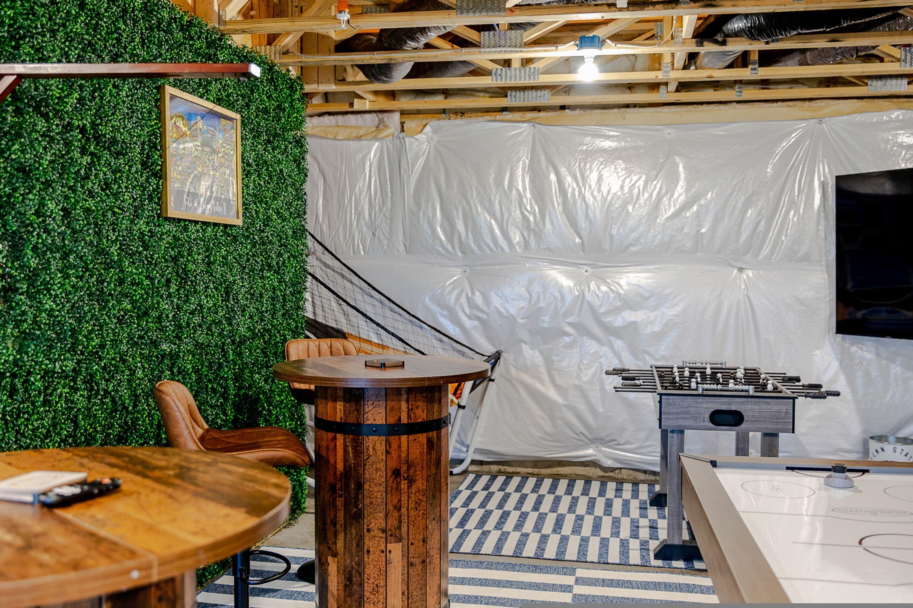 Ein Zimmer mit grüner Wand, einem Holztisch, einer Couch und einem Kicker.