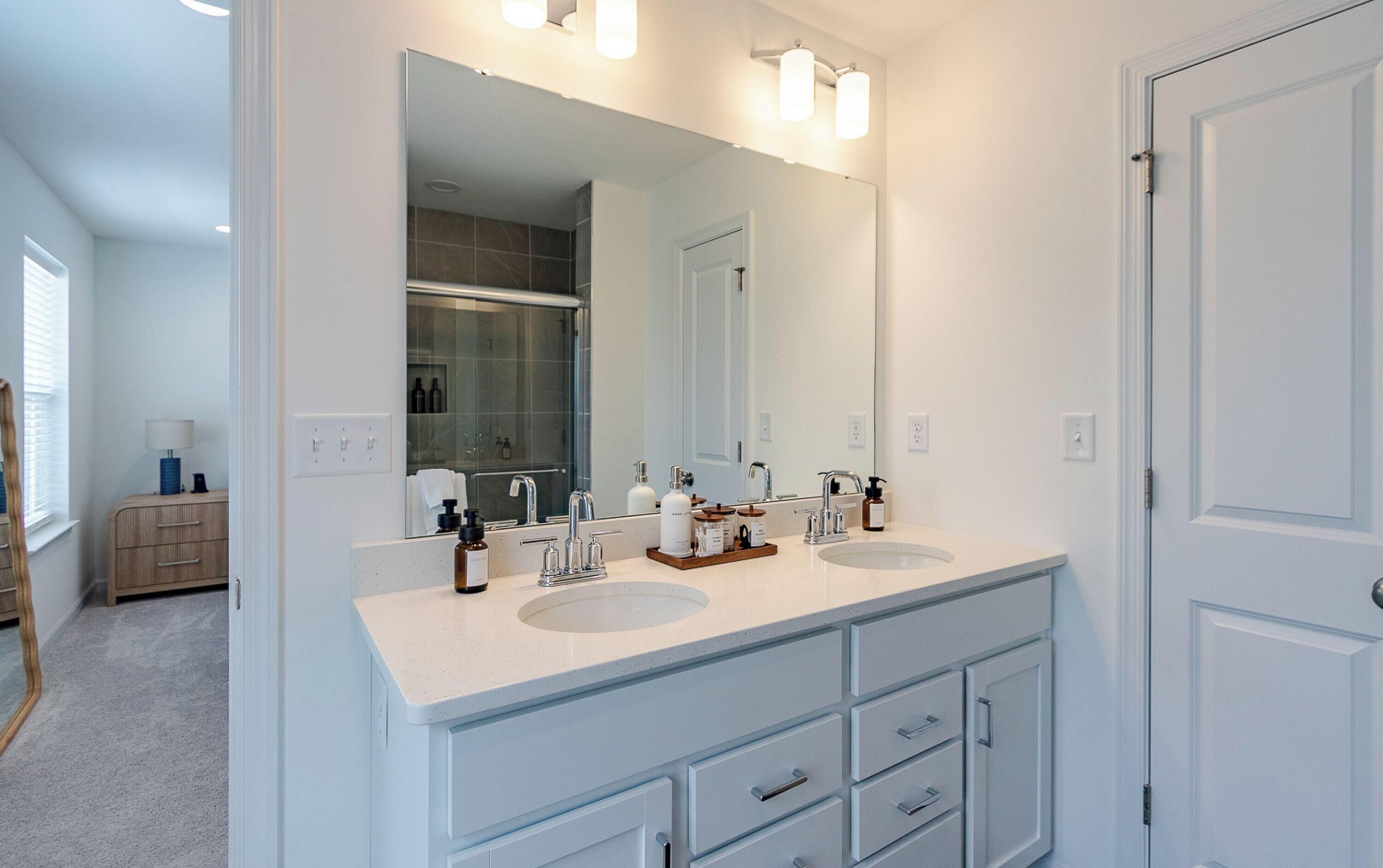 A modern bathroom with two sinks, a large mirror, and a walk-in shower.