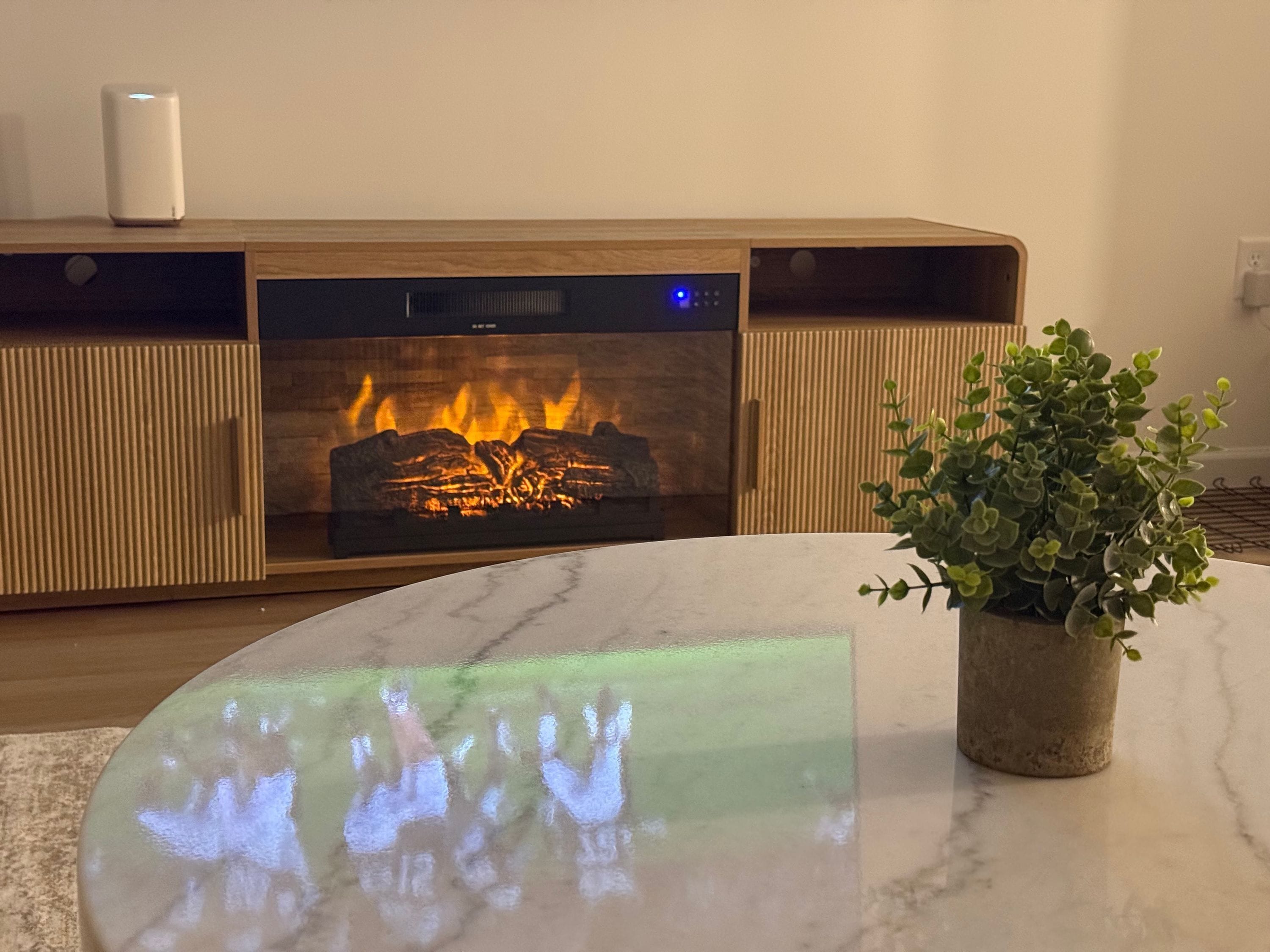 Un salon moderne avec une cheminée intégrée, une table basse en marbre et une plante en pot.