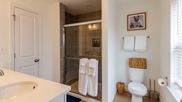 A bathroom with a glass-enclosed shower, a toilet, and a sink.