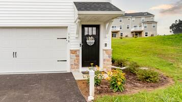 A residential house with a white garage door, a black front door with a Penn State logo, and a stone porch.