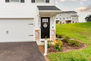 Una casa residencial con una puerta de garaje blanca, una puerta principal negra con el logotipo de Penn State y un porche de piedra.