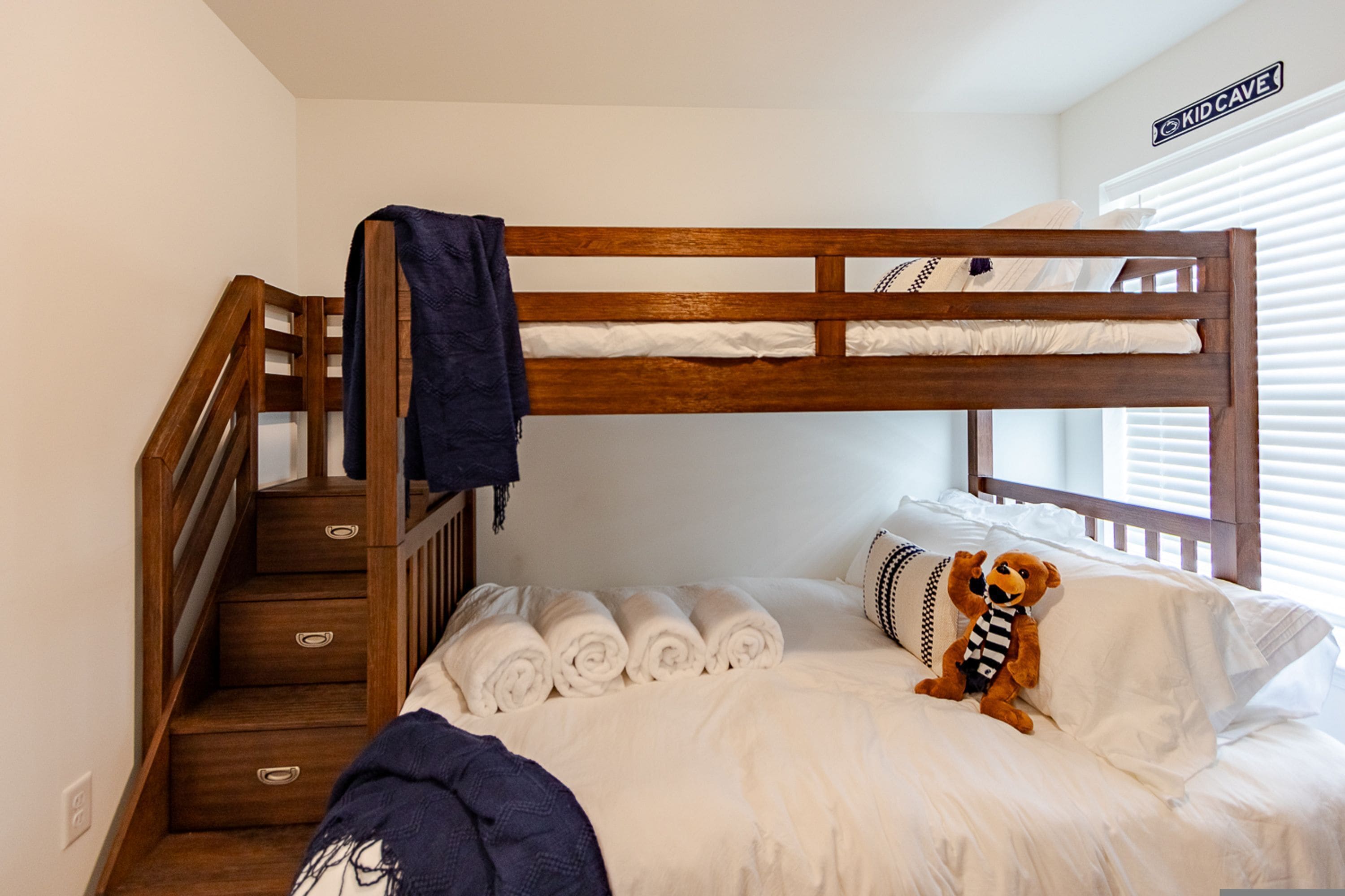 Una cama litera con una escalera de madera y una pequeña escalera que lleva a un nivel inferior.
