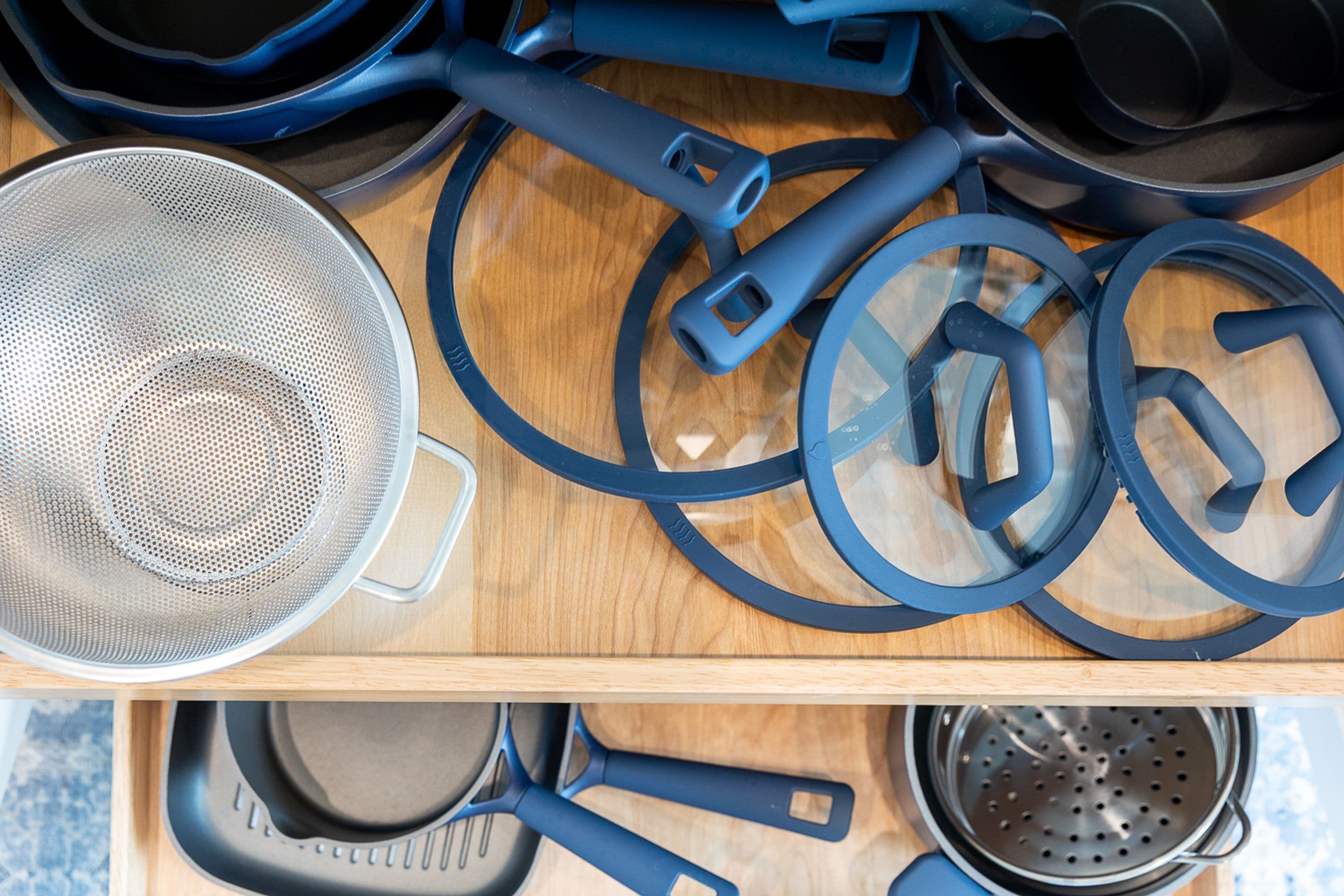 A kitchen with various cookware items including pots, pans, and a colander.