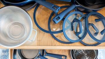A kitchen with various cookware items including pots, pans, and a colander.