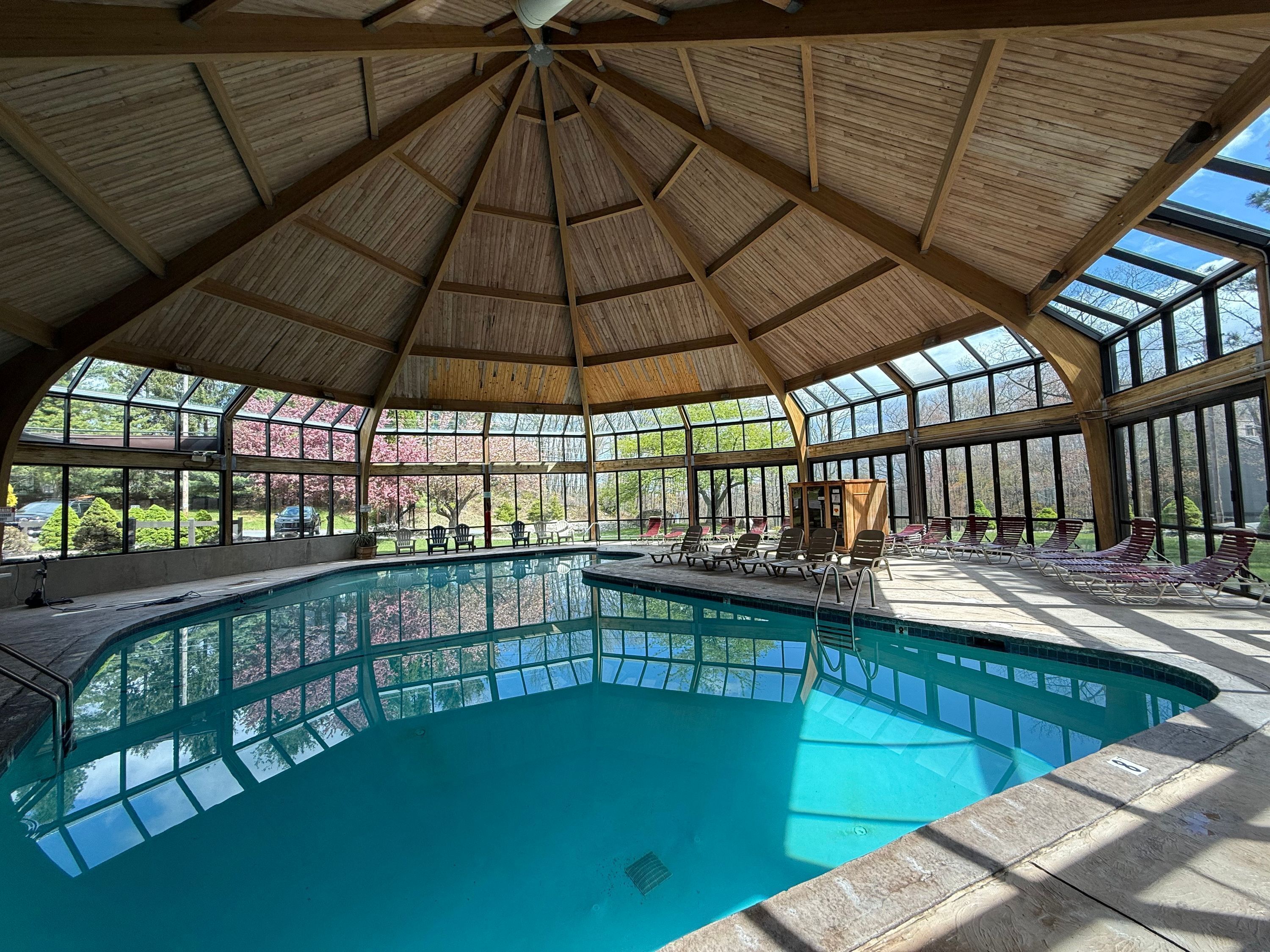 Ein großes Hallenbad mit Holzbalkendecke und Glaswänden.