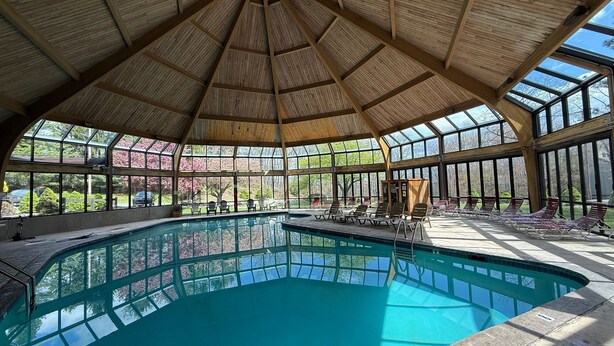 A large indoor swimming pool with a wooden ceiling and glass walls. - Camelback Home Family Friendly Waterpark Arcade (Tannersville)