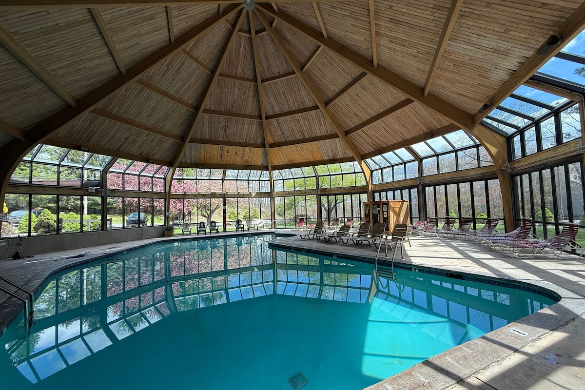 Ein großes Hallenbad mit Holzbalkendecke und Glaswänden.
