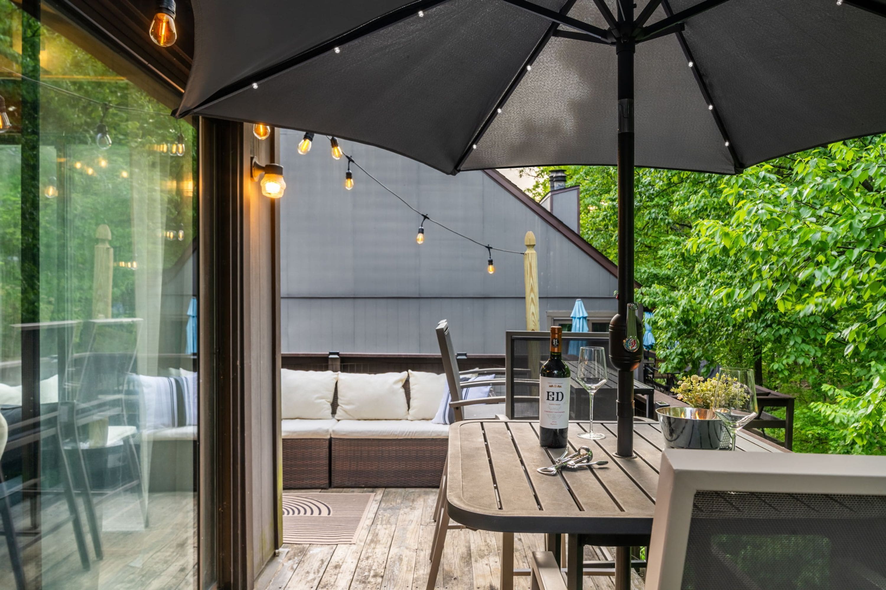 Eine Terrasse im Freien mit Tisch, Stühlen und einem großen Sonnenschirm.