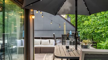 Eine Terrasse im Freien mit Tisch, Stühlen und einem großen Sonnenschirm.