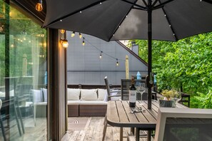 Eine Terrasse im Freien mit Tisch, Stühlen und einem großen Sonnenschirm.