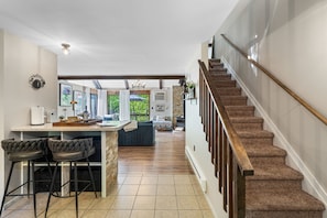 Eine moderne Küche mit Barbereich, einer Treppe und Blick ins Freie.