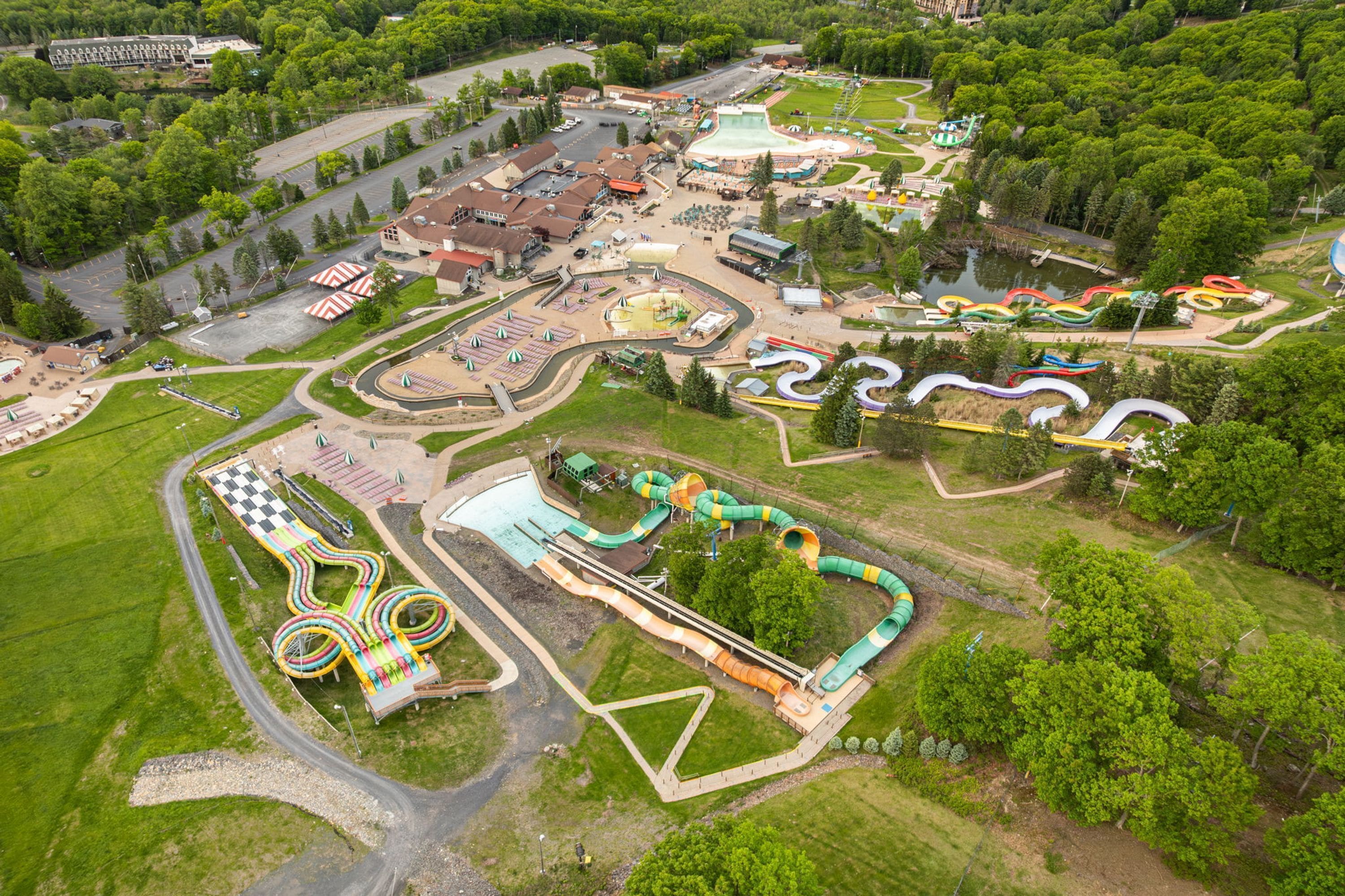 Vista aérea de un parque temático con diversas atracciones, una zona de piscina y un estacionamiento.