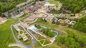 Vista aérea de un parque temático con diversas atracciones, una zona de piscina y un estacionamiento.