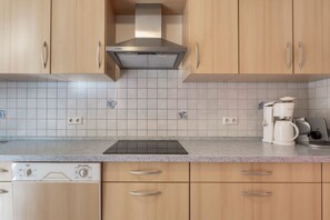 A kitchen with wooden cabinets, a Bosch range hood, a coffee maker, and a dishwasher.