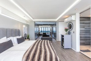 A modern hotel room with a large bed, a view of the sea, and a small kitchenette. - The Blouberg Lookout (Cape Town)
