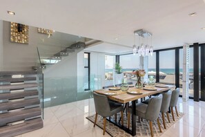 A modern dining area with a wooden table, grey chairs, and a glass staircase. - The Blouberg Lookout (Cape Town)