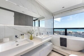 A modern bathroom with a large bathtub, two sinks, and a large mirror. - The Blouberg Lookout (Cape Town)